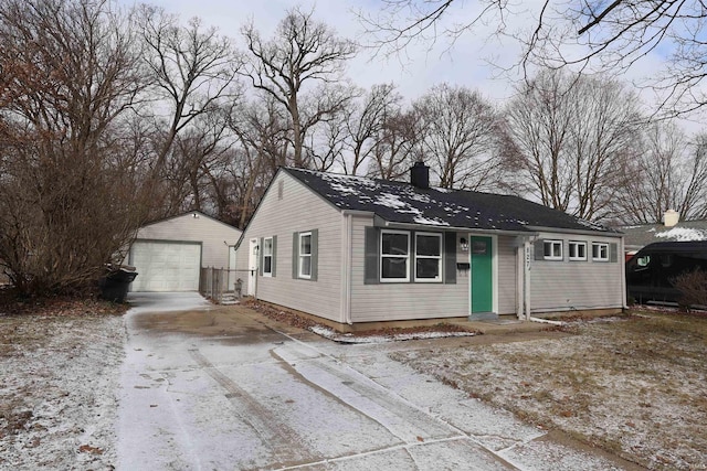 ranch-style home featuring an outbuilding, concrete driveway, a detached garage, and a chimney