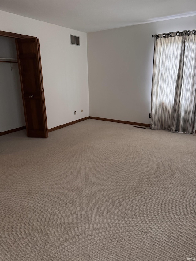 unfurnished bedroom featuring light colored carpet, a closet, visible vents, and baseboards