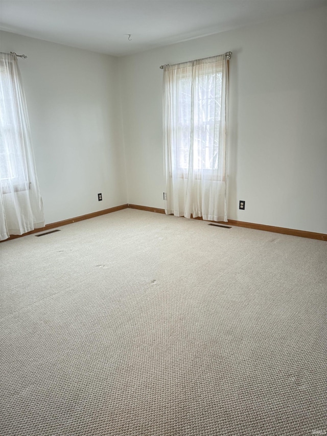 unfurnished room with light colored carpet, visible vents, and baseboards