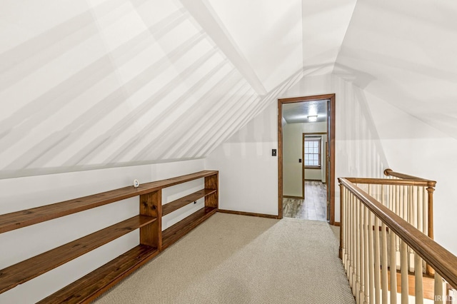 bonus room with lofted ceiling, light colored carpet, and baseboards