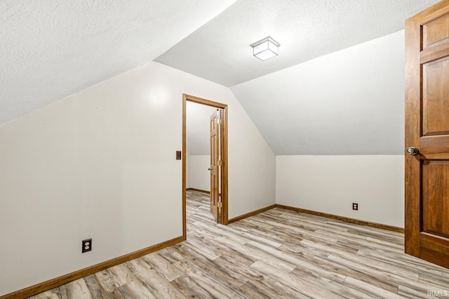 bonus room featuring a textured ceiling, baseboards, lofted ceiling, and light wood-style floors