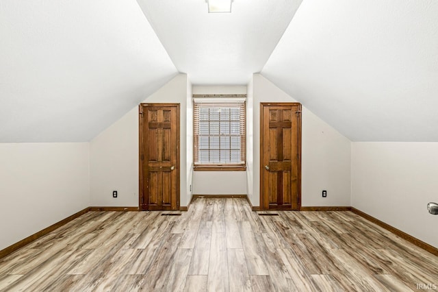 bonus room with light wood-style floors, vaulted ceiling, and baseboards