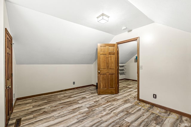 bonus room with lofted ceiling, visible vents, baseboards, and wood finished floors