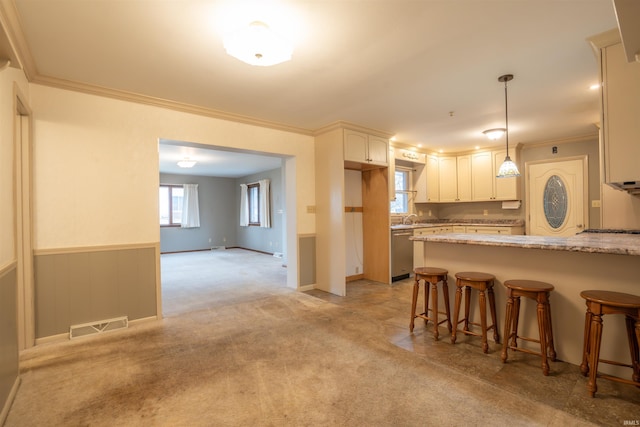 kitchen featuring a breakfast bar area, light carpet, visible vents, stainless steel dishwasher, and wainscoting