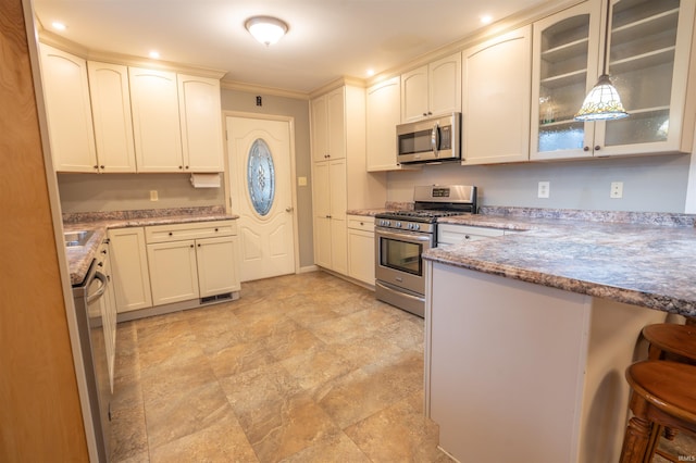 kitchen featuring glass insert cabinets, light stone counters, a peninsula, stainless steel appliances, and a kitchen bar