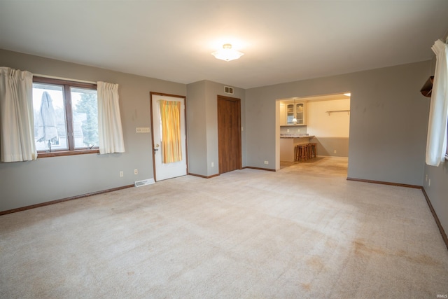 unfurnished bedroom with light carpet, visible vents, and baseboards