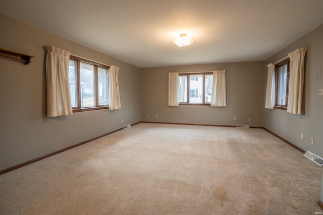 empty room with light carpet, visible vents, and baseboards