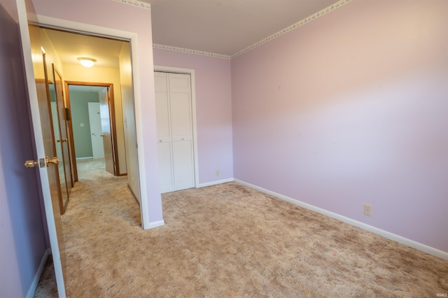 unfurnished bedroom with a closet, carpet flooring, and baseboards