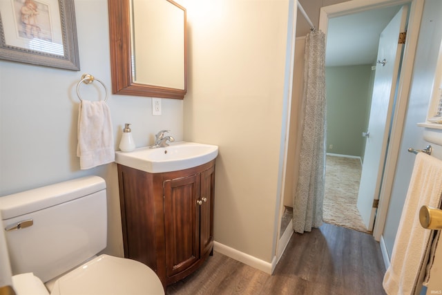 bathroom featuring toilet, curtained shower, wood finished floors, and vanity