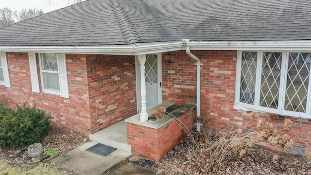 property entrance with brick siding and roof with shingles