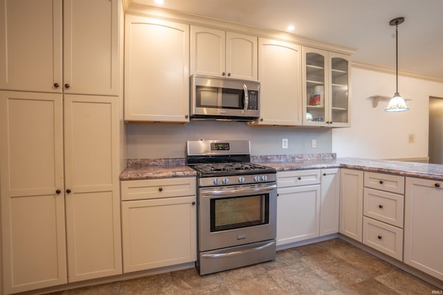 kitchen with glass insert cabinets, appliances with stainless steel finishes, light stone counters, hanging light fixtures, and cream cabinets