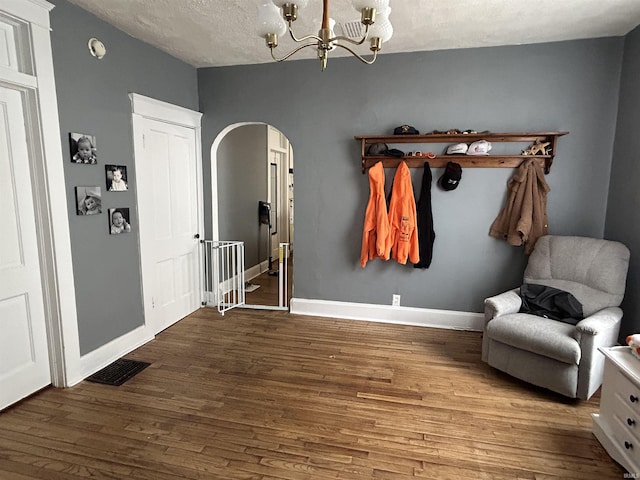 mudroom featuring arched walkways, visible vents, baseboards, and wood finished floors