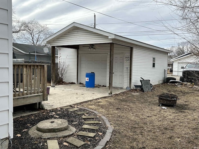 view of outdoor structure with an outdoor fire pit, fence, and an outbuilding