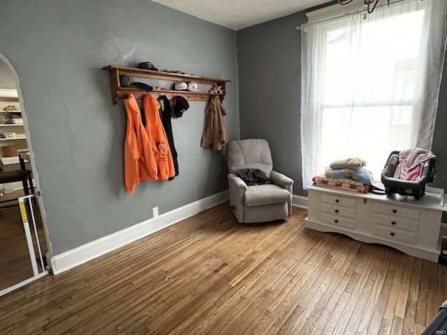 living area with baseboards, arched walkways, and hardwood / wood-style floors