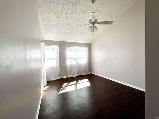 empty room featuring lofted ceiling, a ceiling fan, baseboards, and a textured ceiling