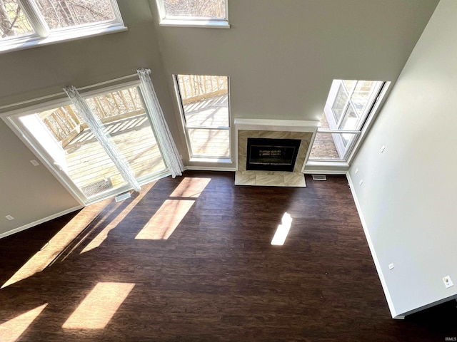 unfurnished living room featuring a premium fireplace, wood finished floors, visible vents, and baseboards