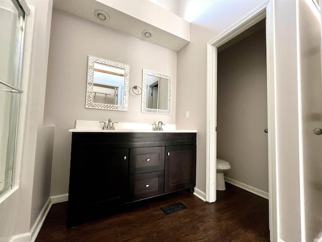 full bathroom featuring baseboards, a sink, toilet, and wood finished floors