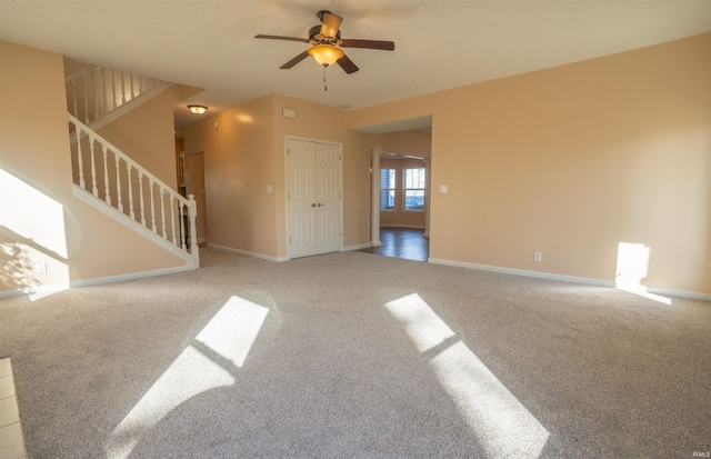 unfurnished living room featuring carpet flooring, stairway, and baseboards