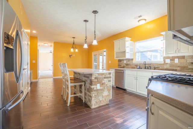 kitchen with stainless steel appliances, plenty of natural light, a kitchen island, and decorative backsplash