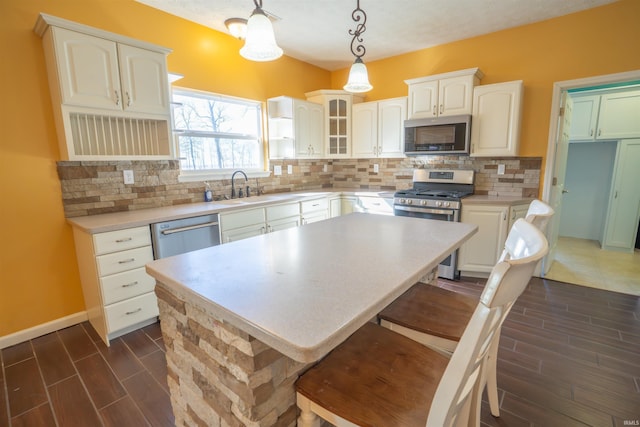 kitchen featuring a sink, appliances with stainless steel finishes, decorative backsplash, wood tiled floor, and glass insert cabinets