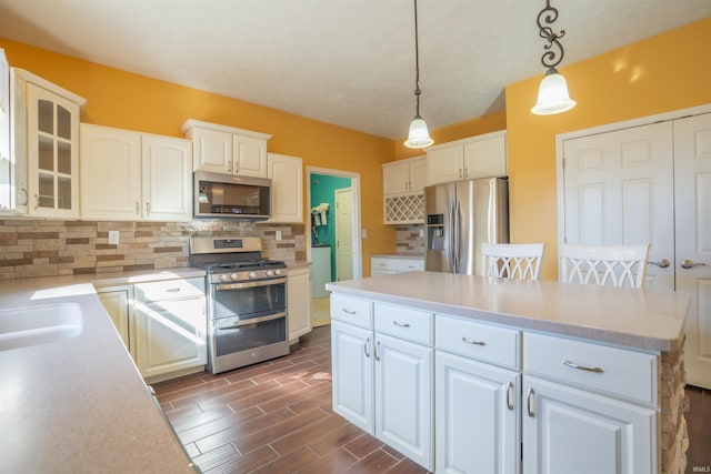 kitchen featuring a center island, decorative backsplash, appliances with stainless steel finishes, wood tiled floor, and white cabinetry