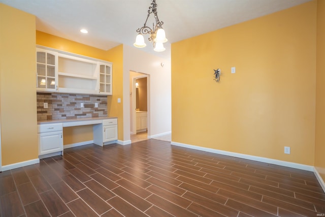 kitchen with tasteful backsplash, built in study area, light countertops, white cabinetry, and open shelves