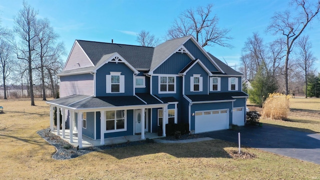 view of front of property featuring a garage, covered porch, a shingled roof, driveway, and a front lawn