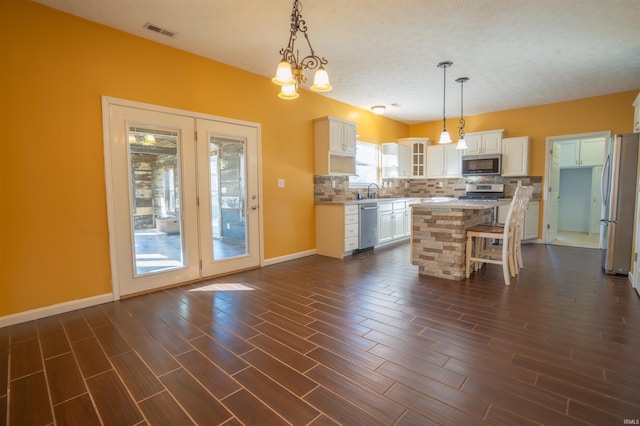 kitchen with stainless steel appliances, visible vents, white cabinets, backsplash, and glass insert cabinets