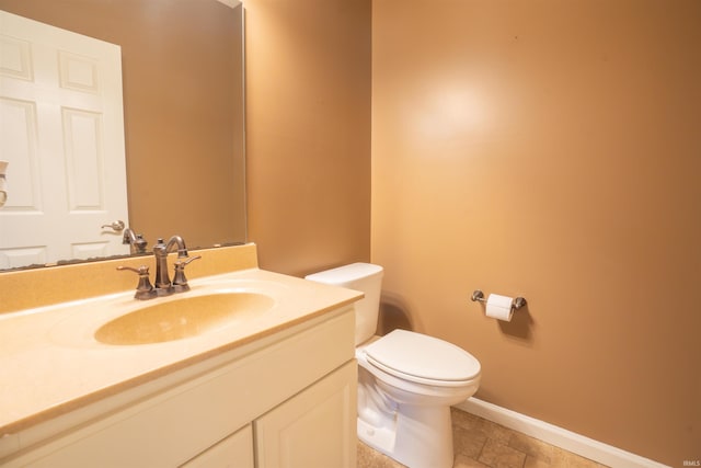 half bathroom featuring toilet, baseboards, and vanity