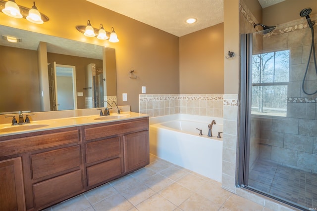 full bath featuring a garden tub, double vanity, a stall shower, a sink, and a textured ceiling