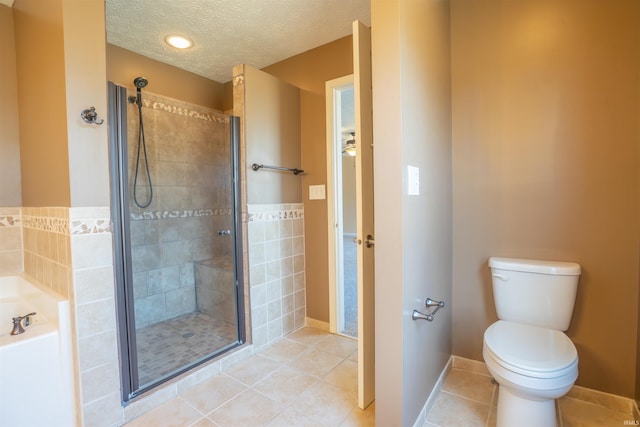 full bathroom with a garden tub, toilet, a shower stall, a textured ceiling, and tile patterned flooring