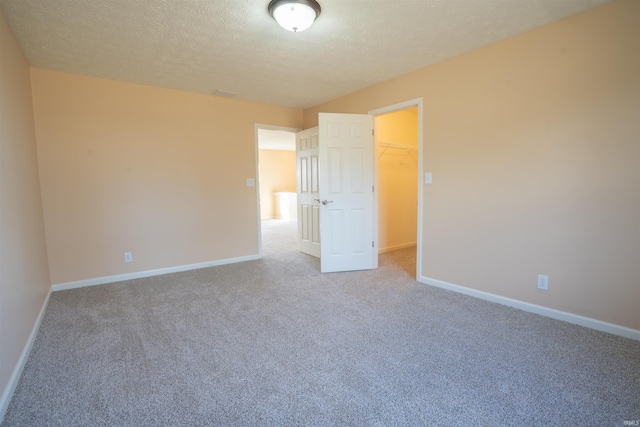 unfurnished bedroom with a spacious closet, carpet, and baseboards