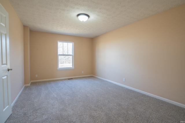 empty room featuring carpet, visible vents, baseboards, and a textured ceiling