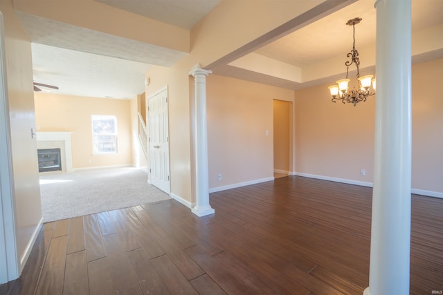 unfurnished room featuring baseboards, dark wood-style flooring, a glass covered fireplace, and ornate columns