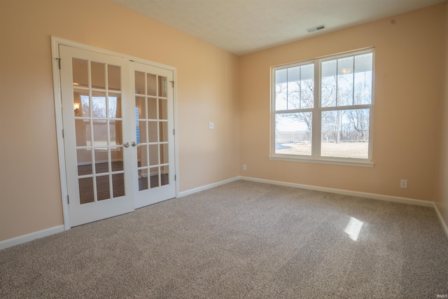 carpeted spare room featuring baseboards, visible vents, and french doors