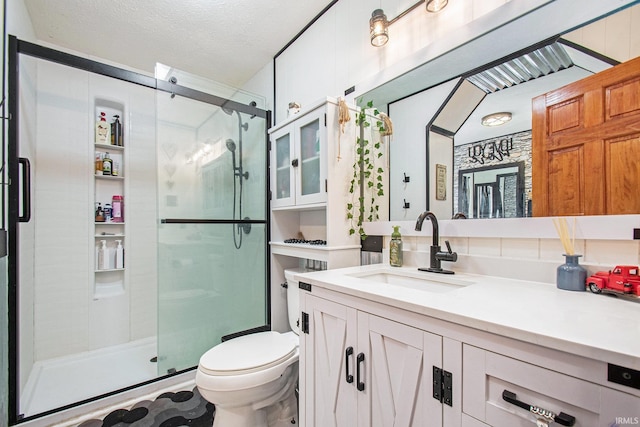 bathroom featuring toilet, a stall shower, a textured ceiling, and vanity