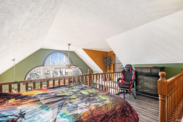 bedroom featuring lofted ceiling, a textured ceiling, and wood finished floors