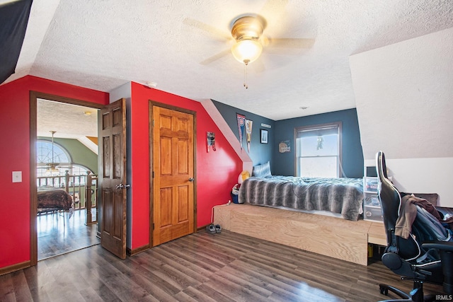 bedroom with vaulted ceiling, ceiling fan, a textured ceiling, and wood finished floors