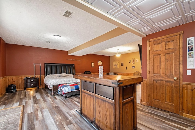 bedroom with an ornate ceiling, wainscoting, wood walls, and wood finished floors