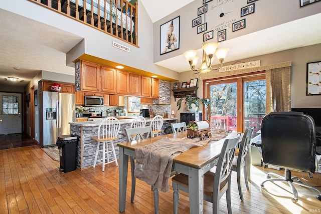 dining area featuring a chandelier, light wood finished floors, and a high ceiling