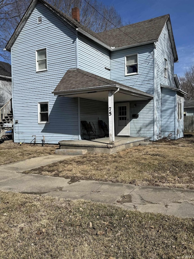 rear view of property with a patio area, a chimney, and roof with shingles