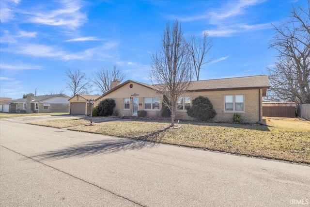 ranch-style home with brick siding, a chimney, fence, driveway, and a front lawn