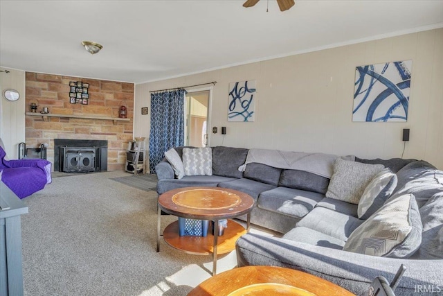 living area with carpet floors, ceiling fan, crown molding, and a stone fireplace