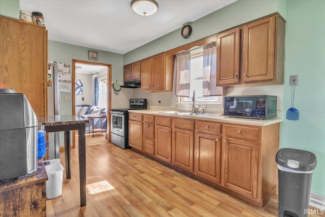 kitchen featuring light wood finished floors, stainless steel electric stove, under cabinet range hood, black microwave, and a sink