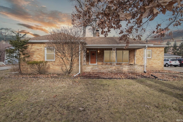 ranch-style home with brick siding and a yard