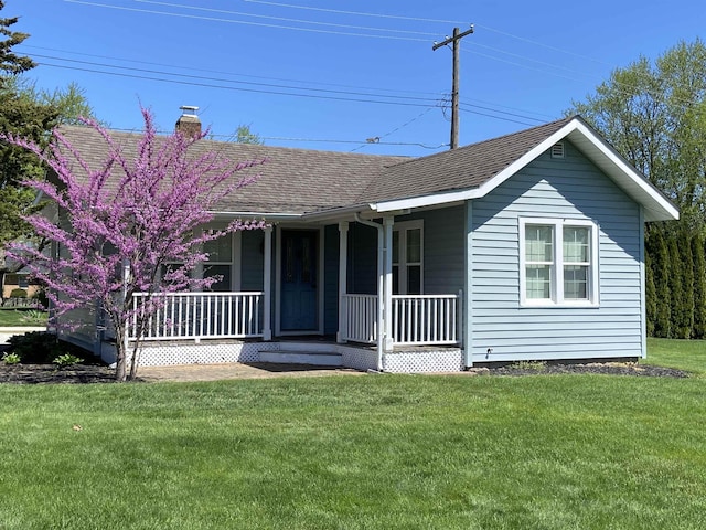 view of front of property featuring a porch, a front yard, roof with shingles, and a chimney