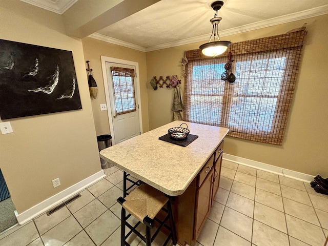 kitchen with light tile patterned floors, visible vents, ornamental molding, a center island, and light countertops