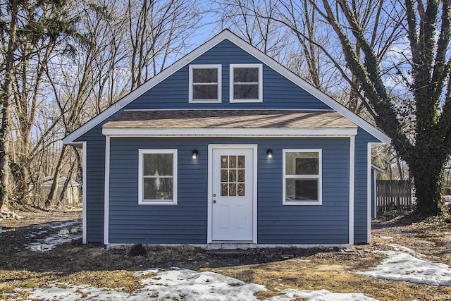 exterior space with a shingled roof and fence