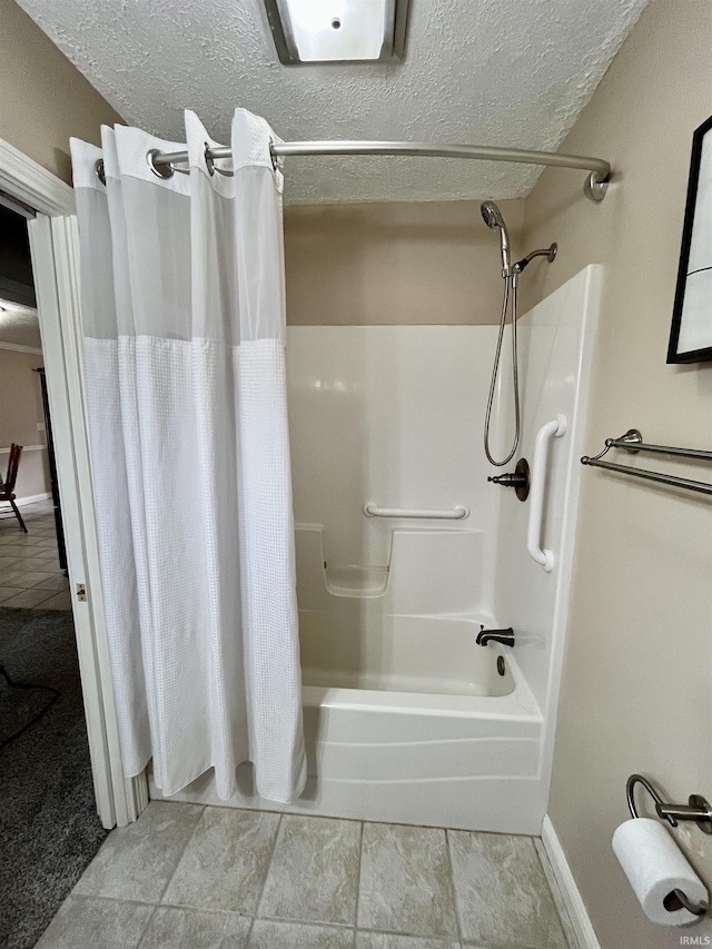 bathroom featuring shower / tub combo, a textured ceiling, and baseboards