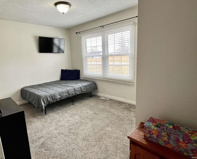 carpeted bedroom featuring visible vents, baseboards, and a textured ceiling